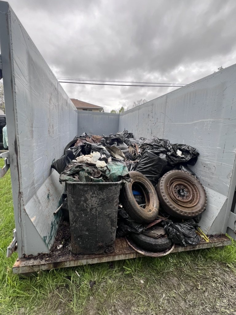 A dumpster filled with tires and trash bags pulled from Johnston Run